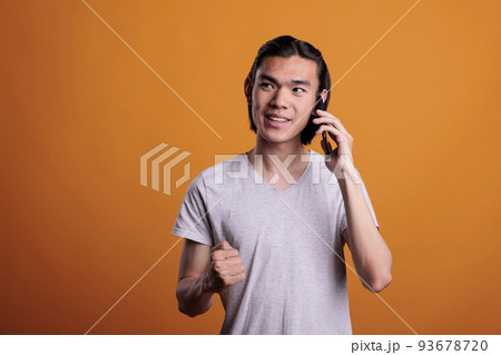 Young smiling man answering phone call on smartphone, hearing good news. Asian teenager chatting on telephone, person with cheerful facial expression having mobile conversation 93678720