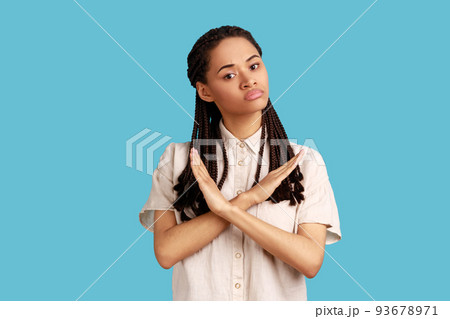 No way, never again. Portrait of determined serious woman with black dreadlocks crossing hands on chest, gesturing x sign, stop this is finish. Indoor studio shot isolated on blue background. 93678971