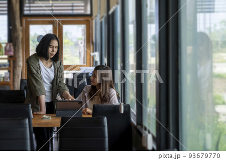Two women discussing business while using a tablet. at a table in a coffee shop 93679770