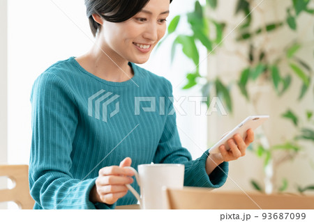 コーヒーを飲みながらスマホを見る女性 コーヒーを飲みながらスマホを見る女性 93687099