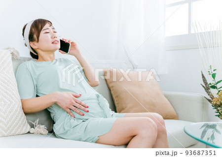 陣痛がきて電話するアジア人女性（腹痛・胃腸炎・食中毒） 93687351