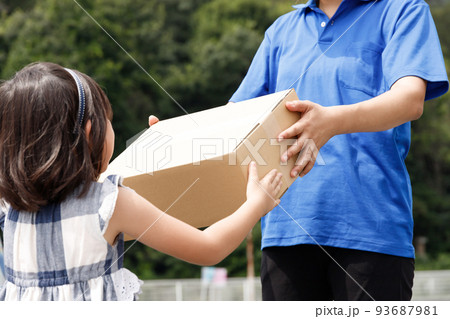 宅配をしている女性が子供に荷物を渡す。子供向け食材の宅配サービス業イメージ。 93687981