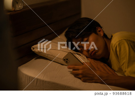 睡眠・寝室のベッドでスマホを見る男性イメージ 93688618