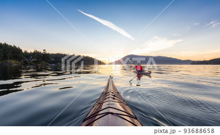 Adventurous Woman on Sea Kayak paddling in the Pacific Ocean. Sunny Summer Sunset 93688658