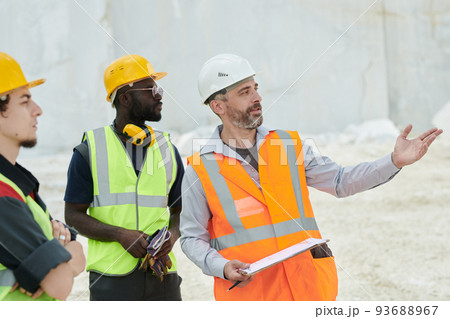 Middle aged foreman in workwear pointing at new industrial equipment Middle aged foreman in workwear pointing at new industrial equipment 93688967