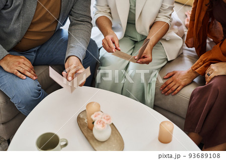 Mature couple in smart casualwear sitting on couch and reading invitation cards 93689108