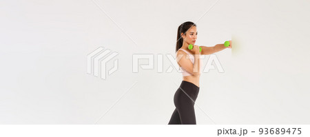 Sport, gym and healthy body concept. Full length of focused female athelte, asian brunette girl doing fitness exercises, workout with dumbbells, productive gym training over white background Sport, gym and healthy body concept. Full length of focused female athelte, asian brunette girl doing fitness exercises, workout with dumbbells, productive gym training over white background 93689475