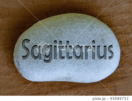 Sagittarius zodiac sign text engraved on a stock with wooden background. Zodiac sign concept. 93689752