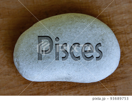 Pisces zodiac sign text engraved on a stock with wooden background. Zodiac sign concept. Pisces zodiac sign text engraved on a stock with wooden background. Zodiac sign concept. 93689753