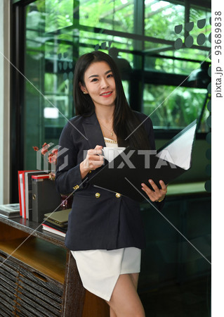 Gorgeous millennial businesswoman standing in corporate office and reading financial reports 93689838