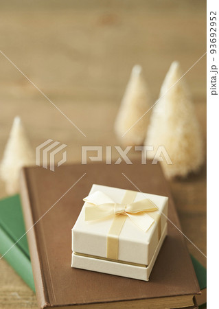本の上に置かれたプレゼントボックスと卓上クリスマスツリー 本の上に置かれたプレゼントボックスと卓上クリスマスツリー 93692952