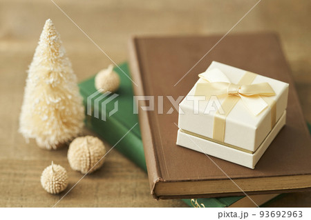 本の上に置かれたプレゼントボックスと卓上クリスマスツリー 本の上に置かれたプレゼントボックスと卓上クリスマスツリー 93692963