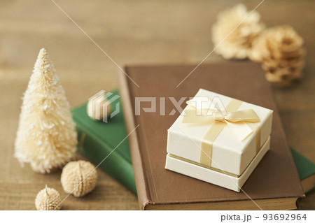 本の上に置かれたプレゼントボックスと卓上クリスマスツリー 本の上に置かれたプレゼントボックスと卓上クリスマスツリー 93692964