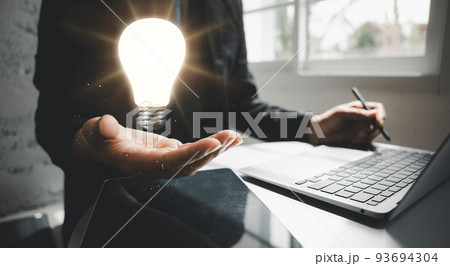 Business man working with laptop computer holding light bulb on hand 93694304