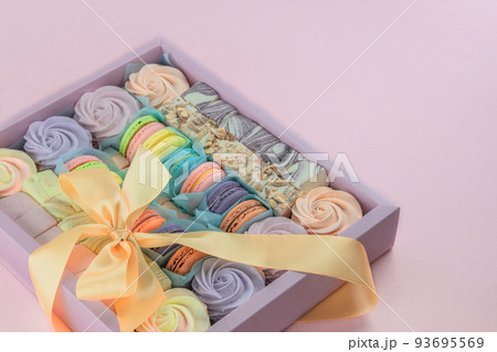 Macaroons and marshmallows in box in pink background, closeup. Traditional colored sweet desserts for present for the holiday. 93695569