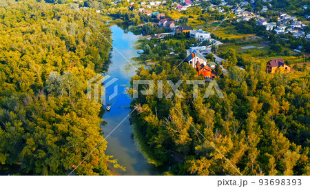 Photo from a drone of a beautiful summer landscape over the river. Beautiful summer landscape with a wide river and green coastline. Aerial photography of the suburban landscape. 93698393