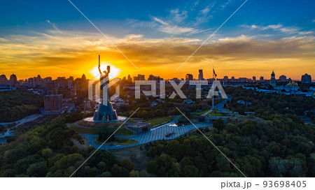 Aerial view to the Motherland statue in the Kiev while summer sunset. The well-known landmarks in Kyiv. Historical monument of Soviet union. Beautiful city Kiev while sunset. Aerial view to the Motherland statue in the Kiev while summer sunset. The well-known landmarks in Kyiv. Historical monument of Soviet union. Beautiful city Kiev while sunset. 93698405