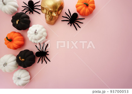 Multicolored pumpkins, a golden skull and black spiders lie on a pink background Multicolored pumpkins, a golden skull and black spiders lie on a pink background 93700053