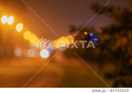 Blurred night cityscape in fog. Bokeh night city road. Night glowing city. Out of focus 93702029