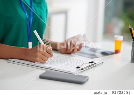 Closeup image of doctor prescribing medicine to patient and writing down dose and intake time Closeup image of doctor prescribing medicine to patient and writing down dose and intake time 93702552