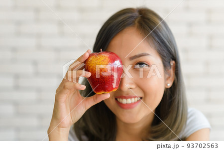 Portrait of smiling beautiful young asian woman holding red apple. close up. 93702563