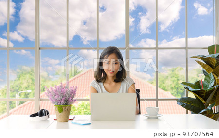 Smiling young asian woman wear casual clothing working with computer laptop in living room at home. Work at home concept. 93702564