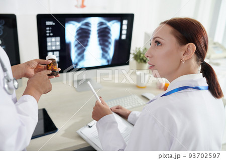 Doctor explaining intern what medicine to subsribe to sick patient 93702597