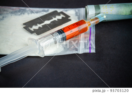 Close-up syringe filled with drug with razor and pack of cocaine. Drug dependence addiction concept. 93703120