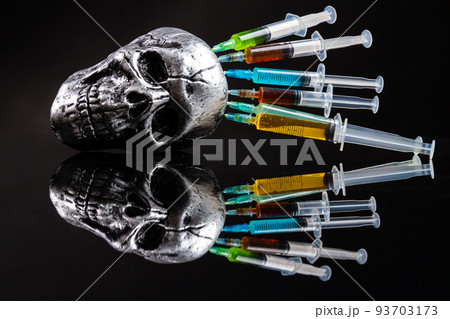Metallic humans skull with colorful stucked syringes on black background. Reflective mirror surface. Death from drugs concept. 93703173
