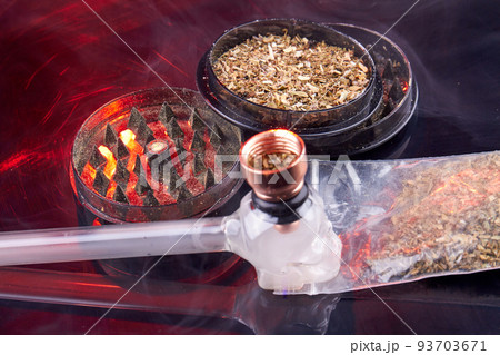 Glass smoking pipe with round grinder filled with weed. Tools for smoking close-up. Glass smoking pipe with round grinder filled with weed. Tools for smoking close-up. 93703671
