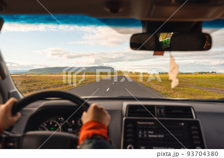Road trip with man driving a car on highway through the field in the evening Road trip with man driving a car on highway through the field in the evening 93704380