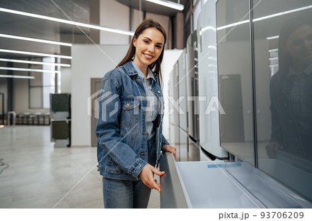 Young attractive woman choosing refrigerator in hypermarket 93706209
