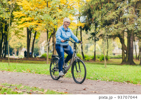 Senior beautiful blonde woman rides a bike in the park, in the woods, in nature, listens to music, spends time actively, plays sports, happy Senior beautiful blonde woman rides a bike in the park, in the woods, in nature, listens to music, spends time actively, plays sports, happy 93707044