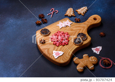 Elements of Christmas decorations, sweets and gingerbread on a wooden cutting board Elements of Christmas decorations, sweets and gingerbread on a wooden cutting board 93707424