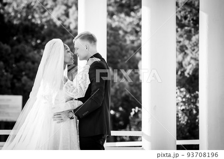 Mixed-racial newlyweds on a walk hugging and looking lovingly at each other, black and white photography 93708196