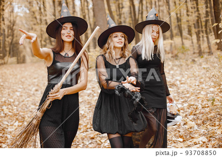 Three girls witches in forest on Halloween. Girls wearing black dresses and cone hats. Witches holding a magician stuff. Three girls witches in forest on Halloween. Girls wearing black dresses and cone hats. Witches holding a magician stuff. 93708850