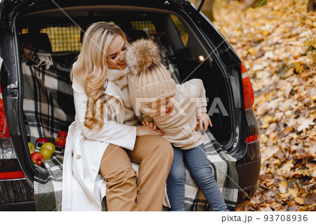 Happy family resting after day spending outdoor in autumn park. Mother and her child boy sitting inside car trunk, smiling. Boy kissing her mother. Happy family resting after day spending outdoor in autumn park. Mother and her child boy sitting inside car trunk, smiling. Boy kissing her mother. 93708936