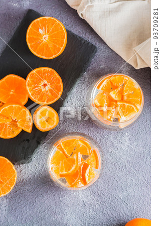 Non-alcoholic cocktail mineral water with pieces of tangerines in glasses and ripe fruits next to on the table. Detox food. Top and vertical view 93709281