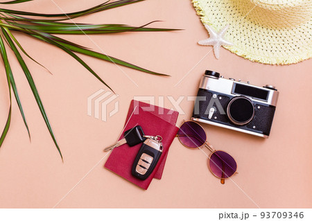 Summer bright travel flat lay with sunglasses, passports, car keys, vintage camera and straw hat on a beige background. Car travel. Top view 93709346
