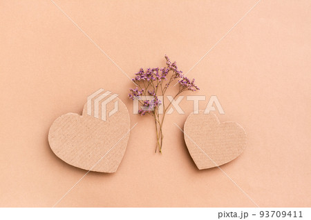 Date concept. Two cardboard hearts and a bouquet of dried flowers between them on a beige background. Top view. 93709411