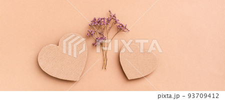 Date concept. Two cardboard hearts and a bouquet of dried flowers between them on a beige background. Top view. Web  banner 93709412