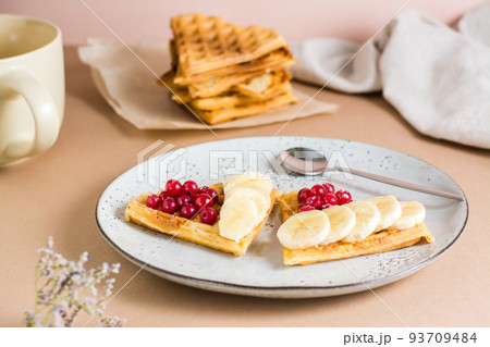 Heart shaped Belgian waffles with red berries and banana on a plate on the table. Valentine's Day. Close-up 93709484