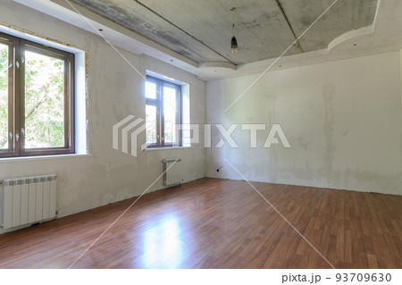 Interior of an empty room during renovation in the room two large windows Interior of an empty room during renovation in the room two large windows 93709630