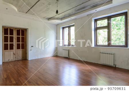 Interior of an empty room during renovation, view of a wall with windows and a wall with a door 93709631