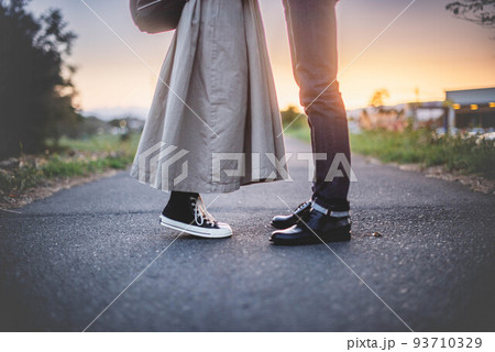男性の目線に合わせようと女性が背伸びする夕暮れのカップル 93710329