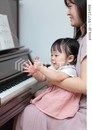 アップライトピアノを弾く1歳の女の子とママ 93713406