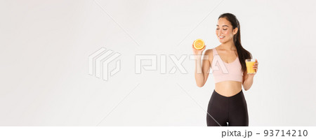 Sport, wellbeing and active lifestyle concept. Portrait of smiling healthy and slim asian girl advice eating healthy food for breakfast, gain energy for workout, hold fresh juice and orange Sport, wellbeing and active lifestyle concept. Portrait of smiling healthy and slim asian girl advice eating healthy food for breakfast, gain energy for workout, hold fresh juice and orange 93714210