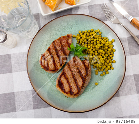 Fried beef cutlet with green peas on plate Fried beef cutlet with green peas on plate 93716488