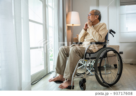 Asian senior man disabled sitting alone in wheelchair looking through window at hospital Asian senior man disabled sitting alone in wheelchair looking through window at hospital 93717608