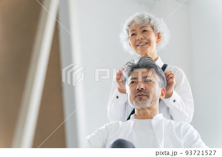 シニア男性をヘアセットするグレイヘアの美容師 93721527